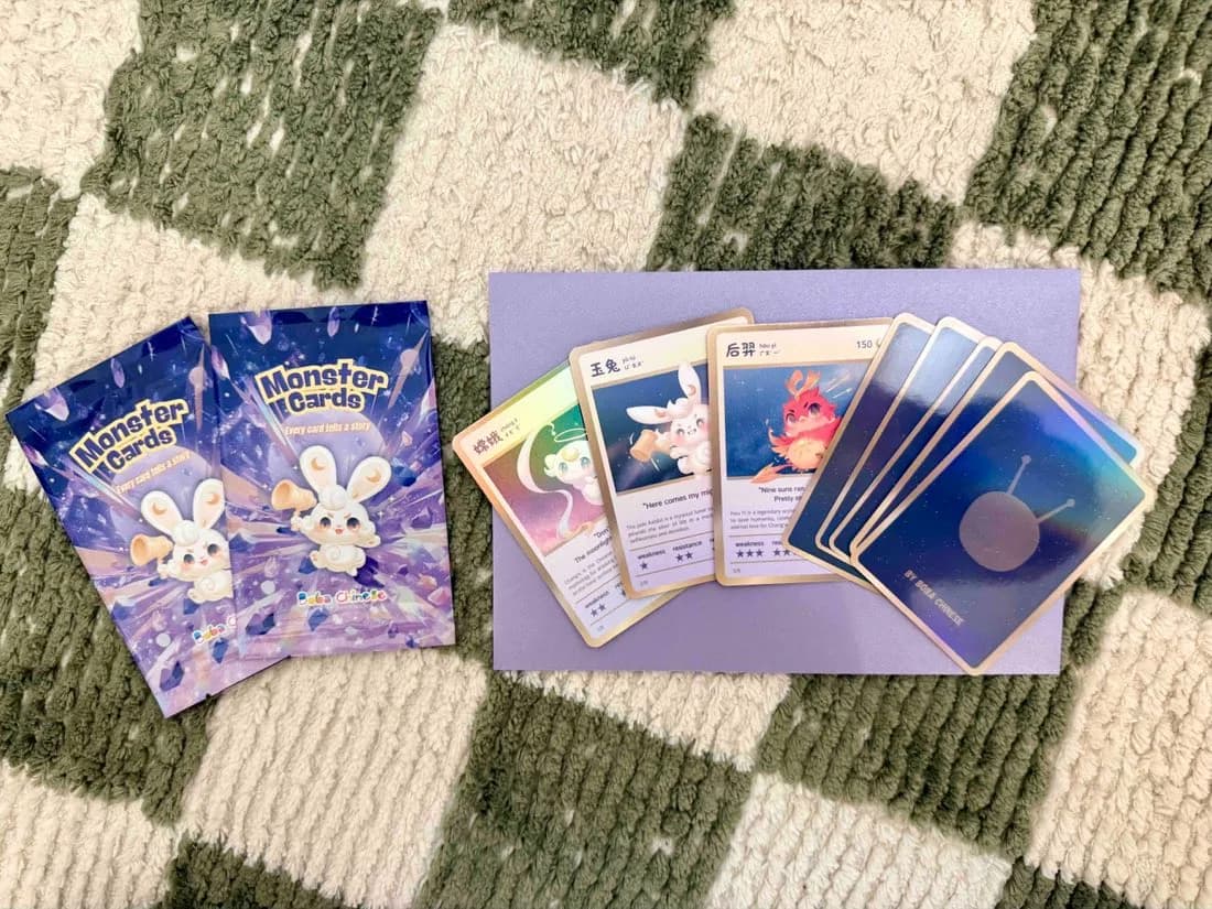 兩包還沒拆的 Monster Cards 卡包、三張正面朝上的卡（嫦娥、玉兔、后羿），還有紫色的寄件信封